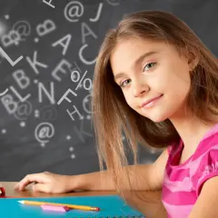 Een meisje leert wat studievaardigheden zijn, omringd door letters en symbolen op een schoolbord.