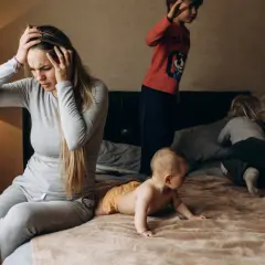 Een moeder met handen in haar hoofd, overdonderd door de drukte van haar kinderen. Een dag met adhd en autisme kan intens zijn.