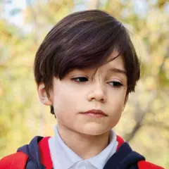Een jongen met autisme kijkt peinzend weg, de schooluitval dreigt.