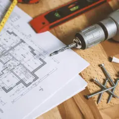 Bouwtekening met een rolmaat, boormachine, schroeven en pluggen. De trap van meter is duidelijk zichtbaar op de tekening.