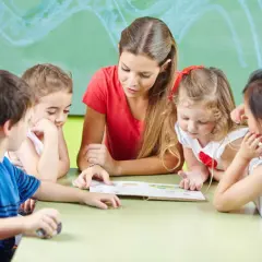 Jonge kinderen luisteren aandachtig naar de juf die voorleest. De leeftijdsgrens basisschool 1 januari is bereikt voor sommigen.