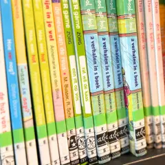 A close-up of a bookshelf filled with colorful children's books, spines facing forward.