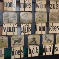 Oude letterkaarten met afbeeldingen, die samen Nederlandse uitdrukkingen vormen zoals 'aap, noot, mies'.