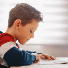 Jongen met dyslexie oefent begrijpend lezen, geconcentreerd op zijn werk.