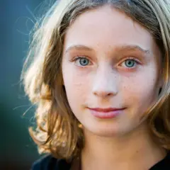 Een meisje met sproeten en blauwe ogen, klaar om de klas over te slaan op de basisschool.