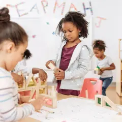 Kinderen bouwen met houten blokken, een typisch voorbeeld van freinet onderwijs waarbij leren door doen centraal staat.