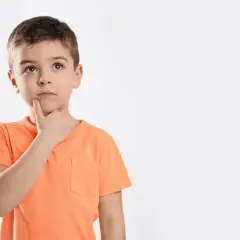 Jongetje met oranje shirt denkt diep na, misschien een beetje traag van begrip, met zijn vinger op zijn kin.