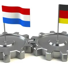 Twee tandwielen, met de Nederlandse en Duitse vlag erop, symboliseren de samenwerking tussen Duitsland en Nederland.