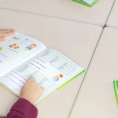 Meisje leest in een boek om technisch lezen te verbeteren. Woorden en zinnen helpen haar met oefenen.