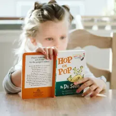 Een meisje van avi m4 leeftijd leest met plezier "Hop on Pop" van Dr. Seuss.
