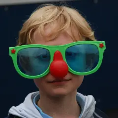 Kind met clownesk gedrag, autisme. Grote groene bril met rode neus, blauwe glazen.