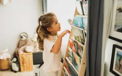 Een meisje met blond haar kijkt aandachtig naar de boekenplank, klaar om een nieuw avontuur te ontdekken. Ze houdt van lezen, kinderen.