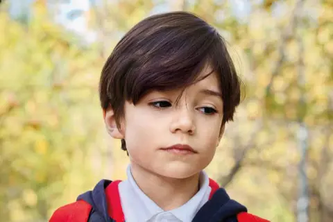 Een jongen met autisme kijkt peinzend weg, de schooluitval dreigt.