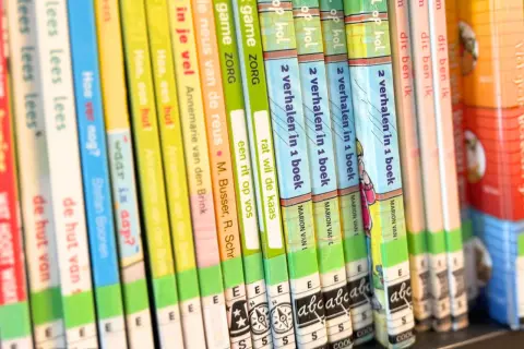 A close-up of a bookshelf filled with colorful children's books, spines facing forward.
