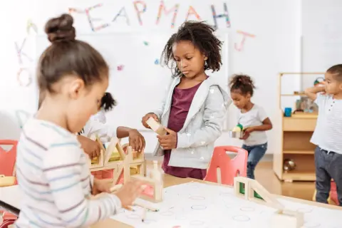 Kinderen bouwen met houten blokken, een typisch voorbeeld van freinet onderwijs waarbij leren door doen centraal staat.