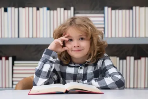 Een jongen met een boek, omringd door boeken. Zijn blik suggereert diepe gedachten, mogelijk over dcd en hoogbegaafdheid.
