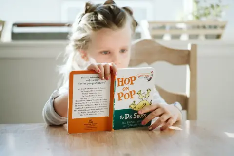 Een meisje van avi m4 leeftijd leest met plezier "Hop on Pop" van Dr. Seuss.