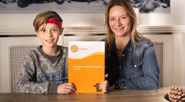 Moeder en zoon houden een oefenboek spelling vast. Vind je het leuk om te leren spellen?
