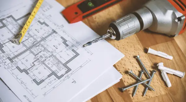 Bouwtekening met een rolmaat, boormachine, schroeven en pluggen. De trap van meter is duidelijk zichtbaar op de tekening.