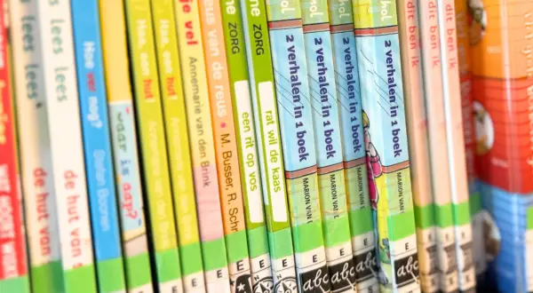 A close-up of a bookshelf filled with colorful children's books, spines facing forward.