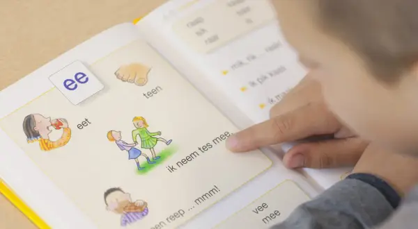 Kind leert woordenschat groep 3 uit een boekje. De letter 'ee' staat centraal, met illustraties van eten en spelen.