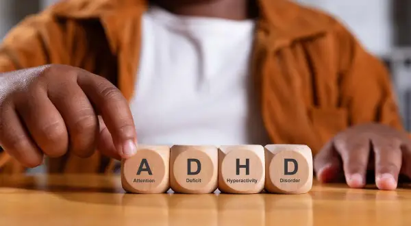 Een peuter met adhd legt blokjes met de letters A, D, H, D.
