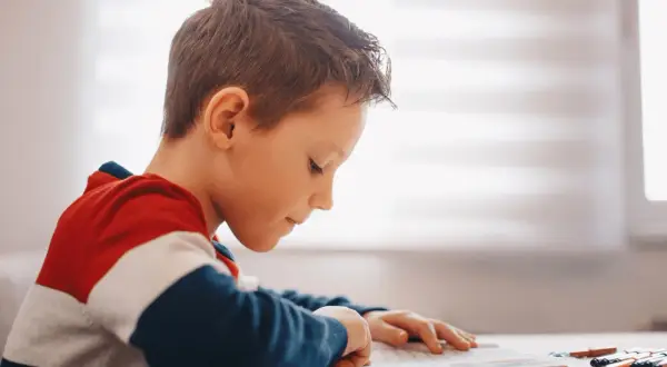 Jongen met dyslexie oefent begrijpend lezen, geconcentreerd op zijn werk.