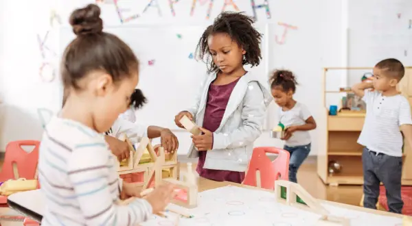 Kinderen bouwen met houten blokken, een typisch voorbeeld van freinet onderwijs waarbij leren door doen centraal staat.