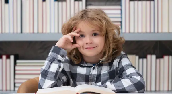 Een jongen met een boek, omringd door boeken. Zijn blik suggereert diepe gedachten, mogelijk over dcd en hoogbegaafdheid.