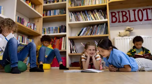 Kinderen genieten van leesplezier in de bibliotheek, omringd door boeken.