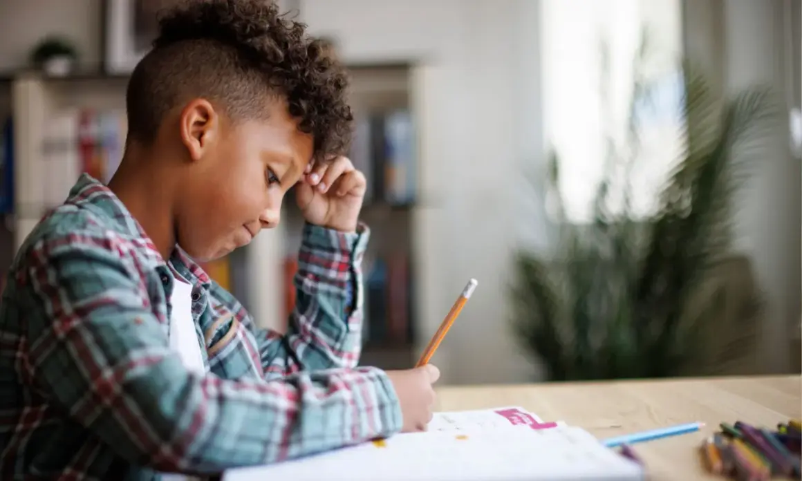 Jongen met krullend haar verdiept in zijn huiswerk, een potlood in zijn hand, navigeert door de wereld van getallen.