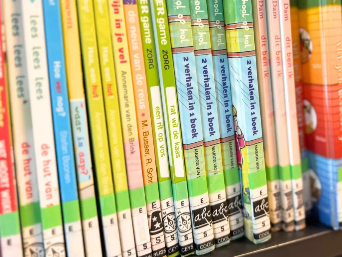 A close-up of a bookshelf filled with colorful children's books, spines facing forward.