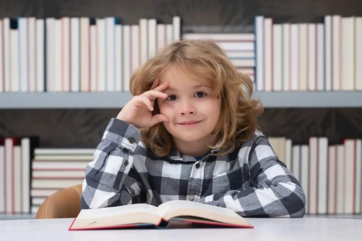 Een jongen met een boek, omringd door boeken. Zijn blik suggereert diepe gedachten, mogelijk over dcd en hoogbegaafdheid.