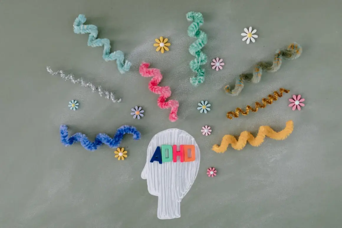 Kleurrijke linten en bloemen omringen een hoofdprofiel met de letters "ADHD". Dit symboliseert de zoektocht naar een kind behandeling.