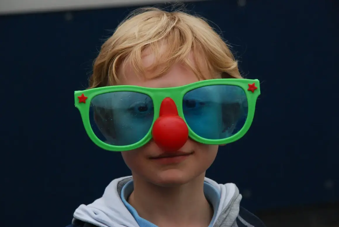 Kind met clownesk gedrag, autisme. Grote groene bril met rode neus, blauwe glazen.