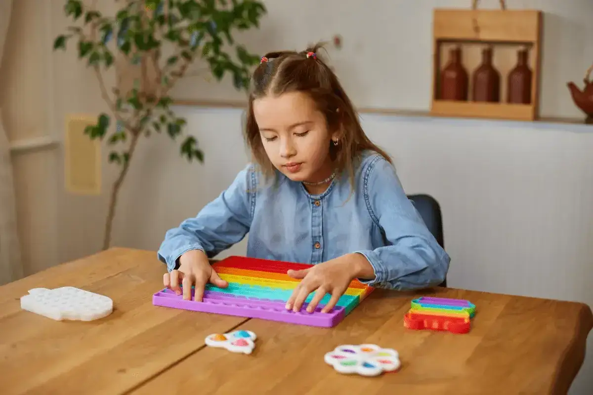 Meisje met autisme speelt met pop-it speelgoed, wat helpt bij het kalmeren van hoofd bonken.