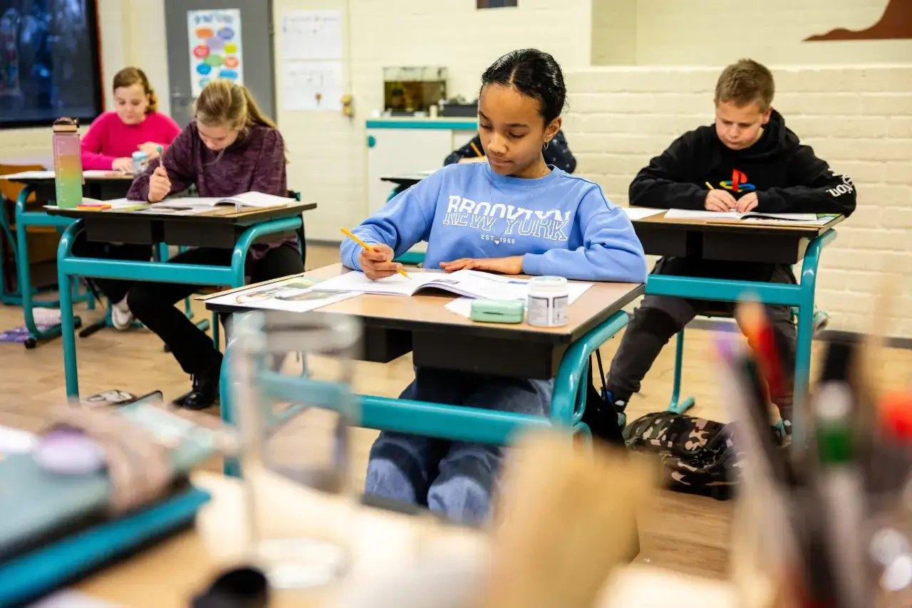 Kinderen leren in de klas. Een meisje met een blauwe trui met 