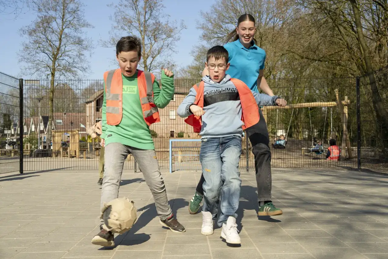 Kinderen spelen met een bal op het schoolplein, wat betekent bso: een leuke middag vol spel en plezier na schooltijd.