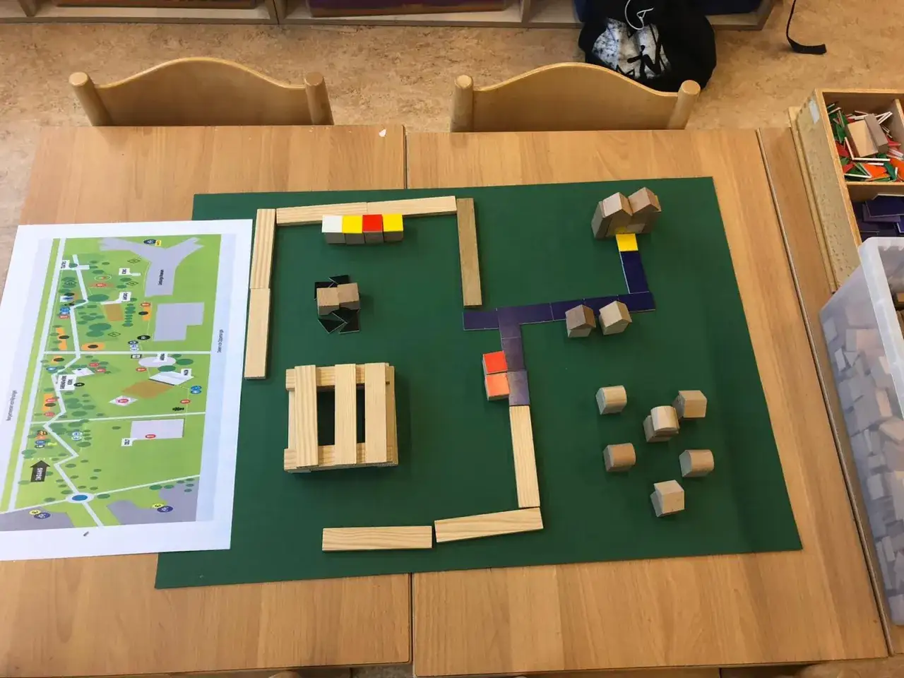 Kinderen bouwen met houten blokken op een groene mat, een plattegrond ligt ernaast. Een leuke activiteit voor de grote rekendag!