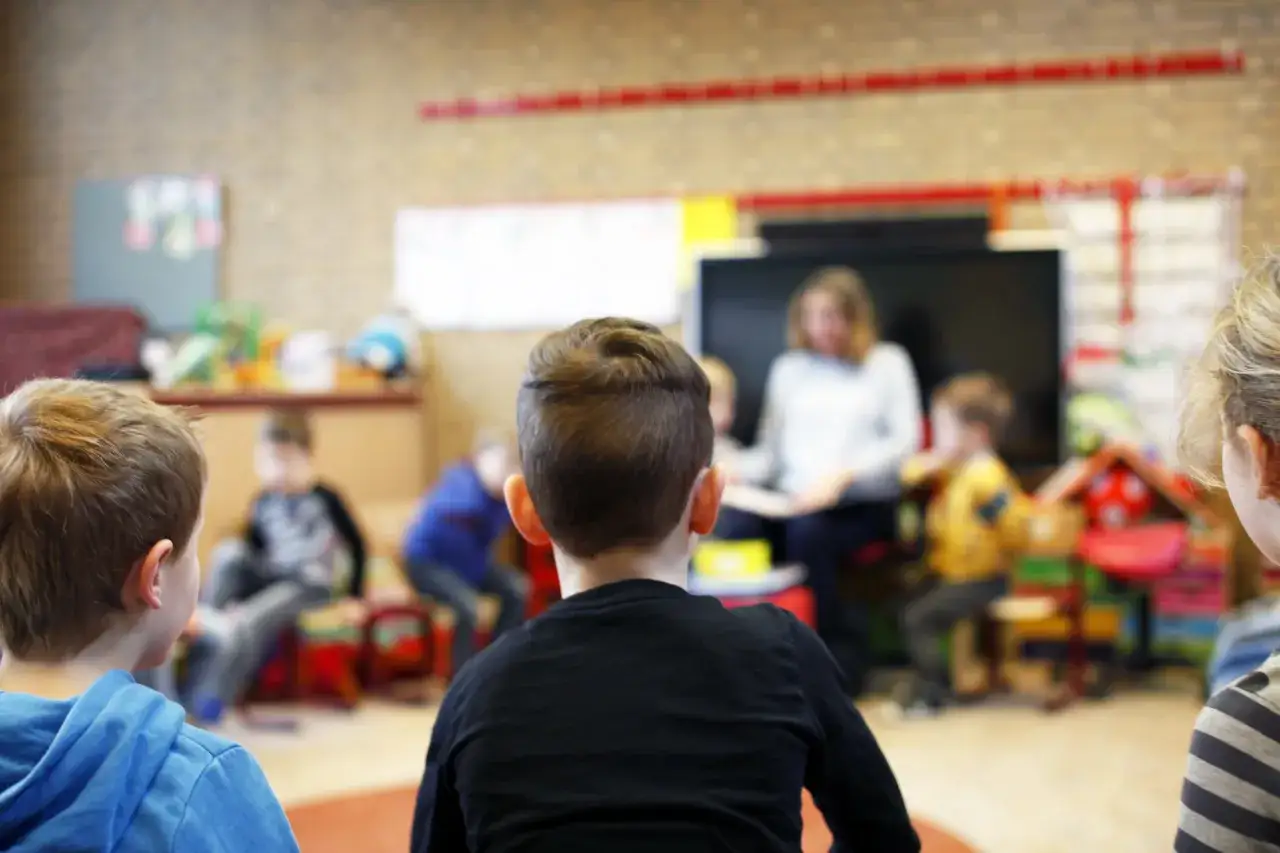 Kinderen luisteren aandachtig naar de juf tijdens begeleid hardop lezen in de klas.