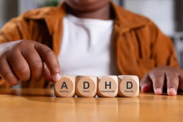 Een peuter met adhd legt blokjes met de letters A, D, H, D.