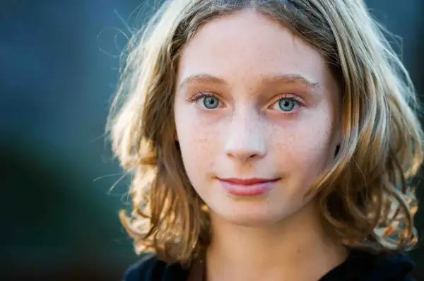 Een meisje met sproeten en blauwe ogen, klaar om de klas over te slaan op de basisschool.
