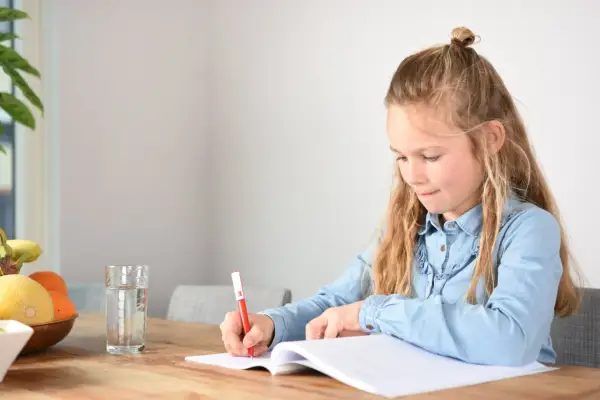 Een meisje schrijft in haar schrift, geconcentreerd op het oplossen van ongelijknamige breuken. Een glas water en fruit staan klaar.